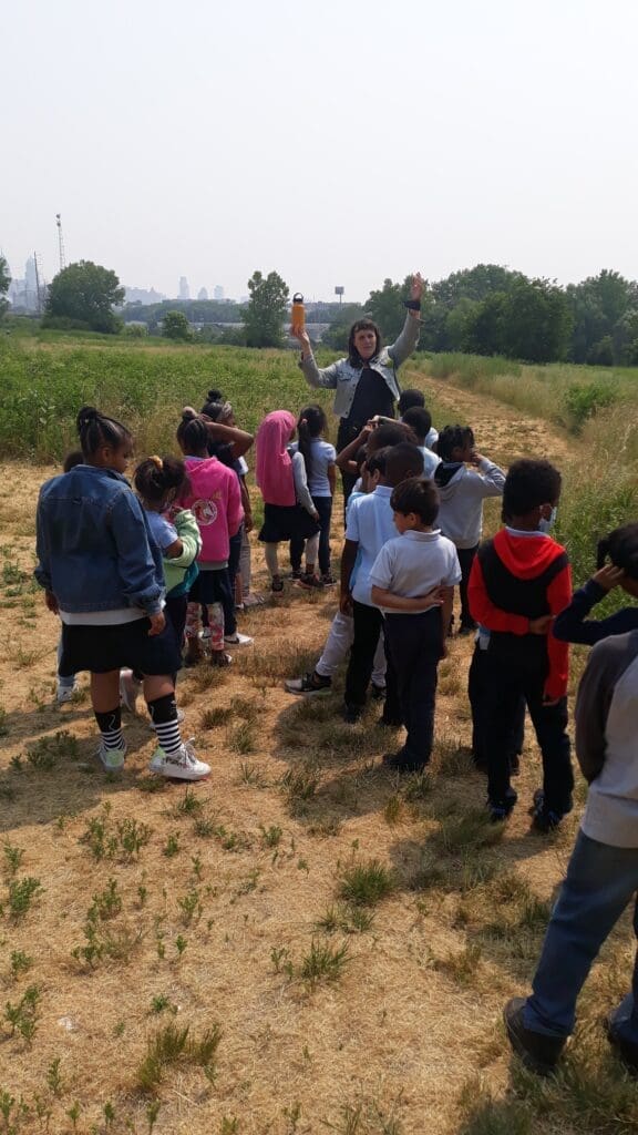 First-grade students in the Bartram's Garden meadow with a staff educator.