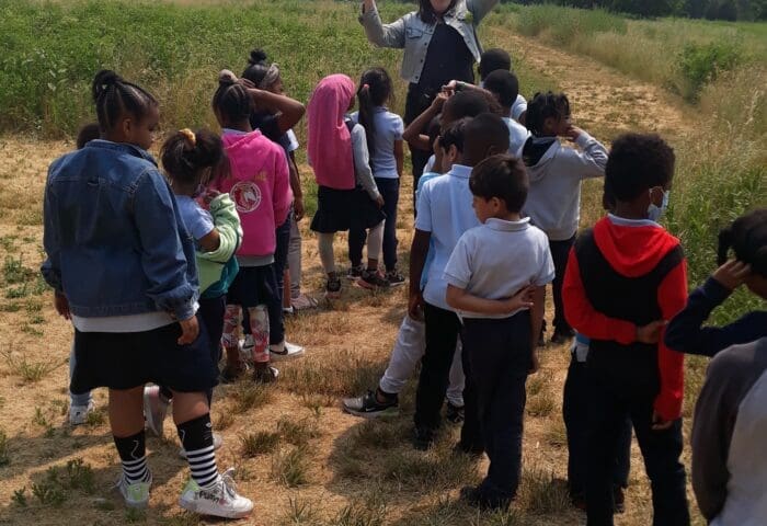 First-grade students in the Bartram's Garden meadow with a staff educator.